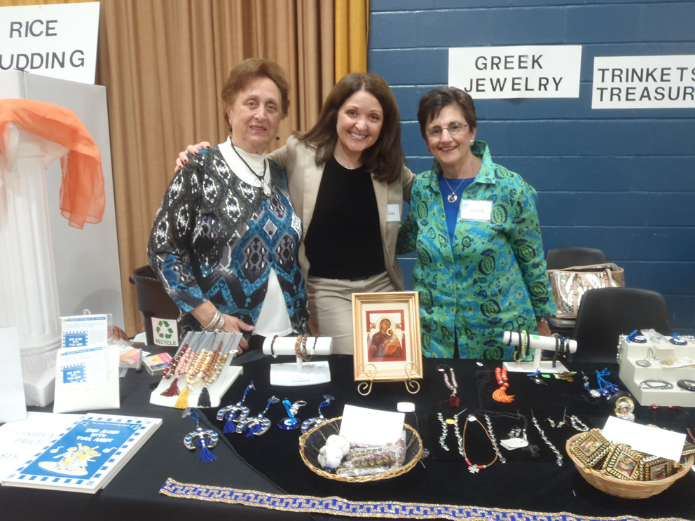 Parishioners at a festival table displaying Greek jewelry.